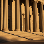 Sunlit stone steps and tall fluted columns of a neoclassical government building at dusk.