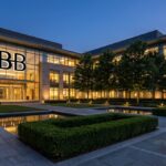 Modern glass-front office building at dusk with the BB logo, landscaped courtyards and reflecting pools.