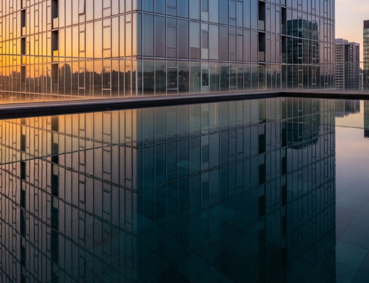 Infinity-edge rooftop pool on a tall glass building, reflecting the sunset-lit city skyline in the water.