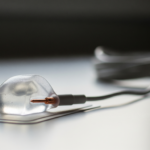 Close-up of a clear contact lens resting on a blister pack with a blurred lens case in the background.