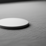 White circular disc resting on a gray textured fabric, close-up.
